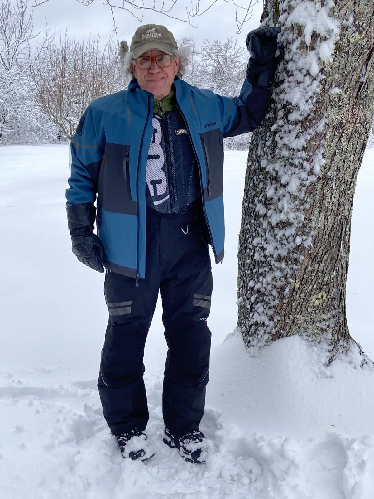 un homme habillé de la veste 3-en-1 contego et de la salopette hoback debout près d'un arbre