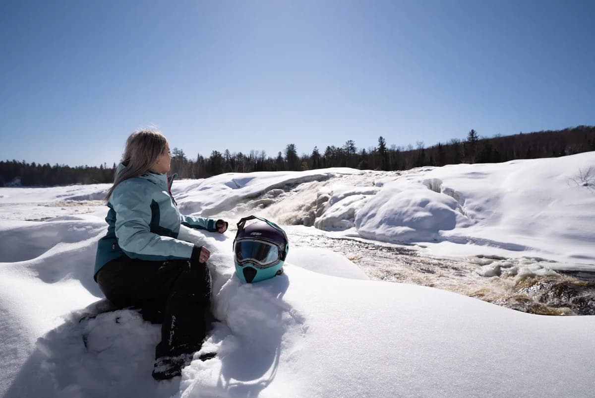 Une femme est assise dans la neige près des Chutes César dans les Laurentides