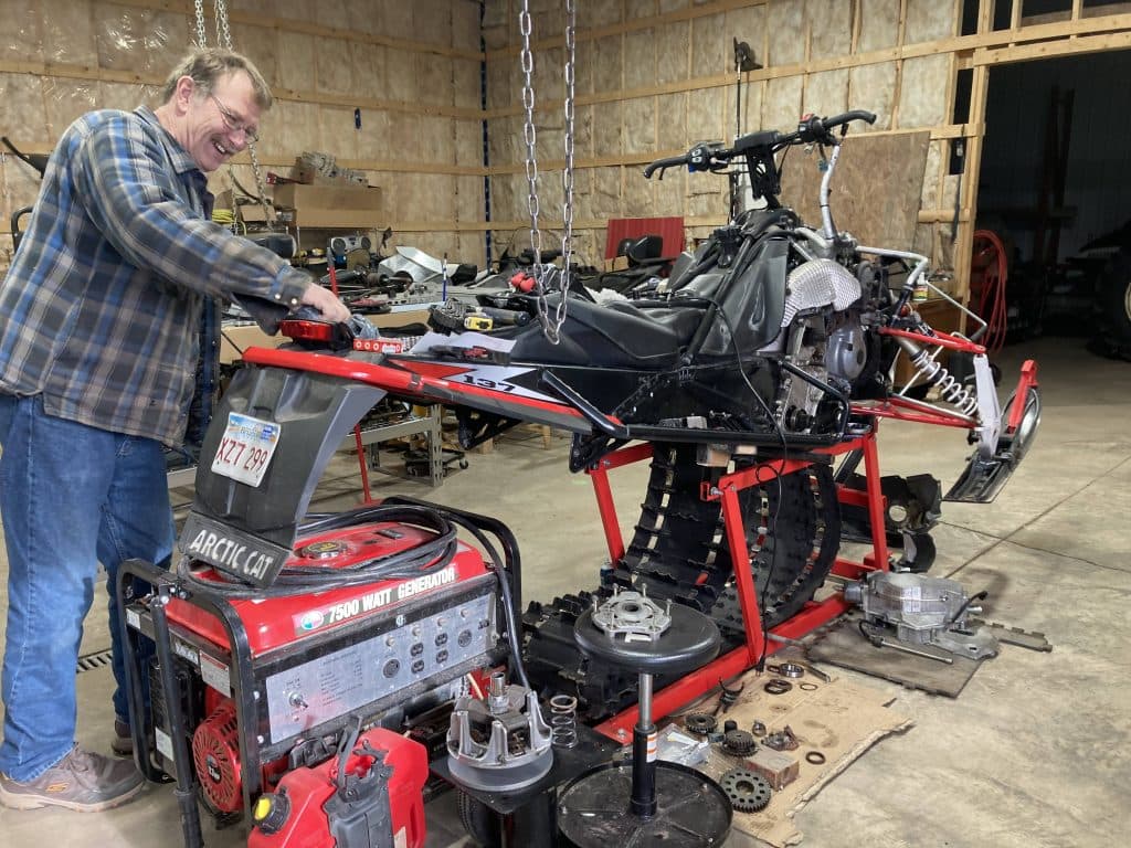 Rock Fowler qui travaille sur sa motoneige dans un garage