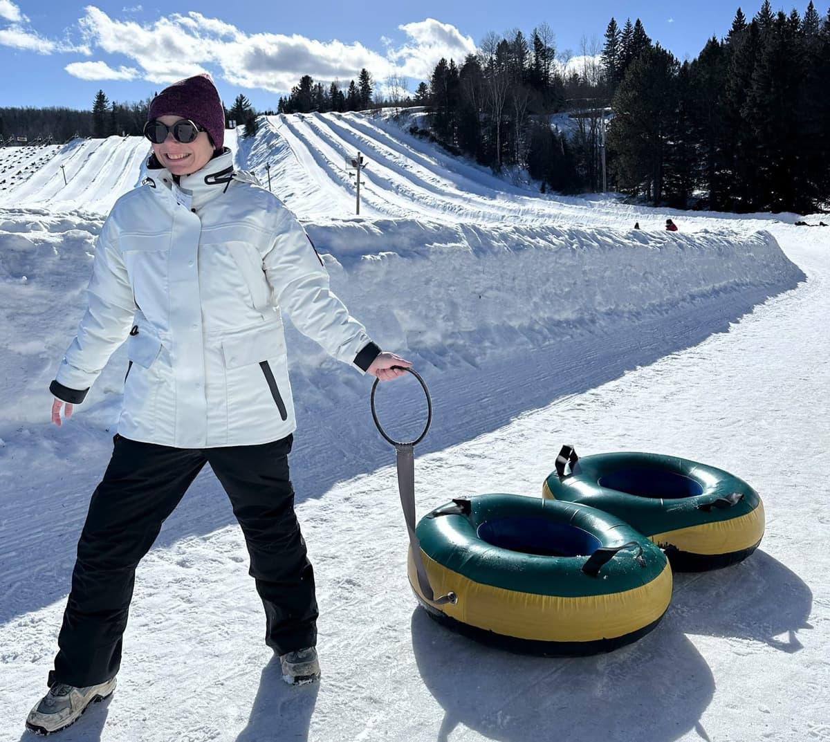 une femme portant le manteau typha x kanuk qui traîne des tubes à glissade