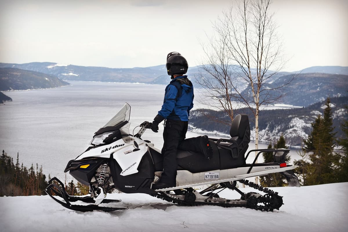 Motoneigiste admirant le fjord enneigé du Saguenay, un incontournable de la saison motoneige au Saguenay–Lac-Saint-Jean.