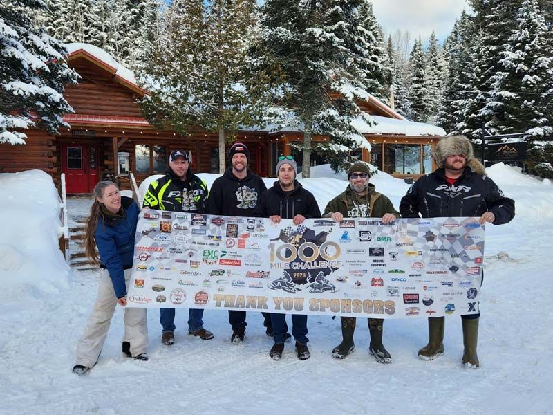 6 participants du 1000 mile challenge qui tiennent une bannière remerciant les commanditaires