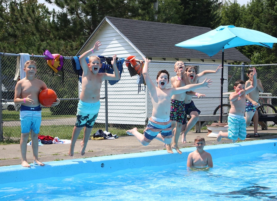 des enfants qui sautent dans une piscine en grimaçant