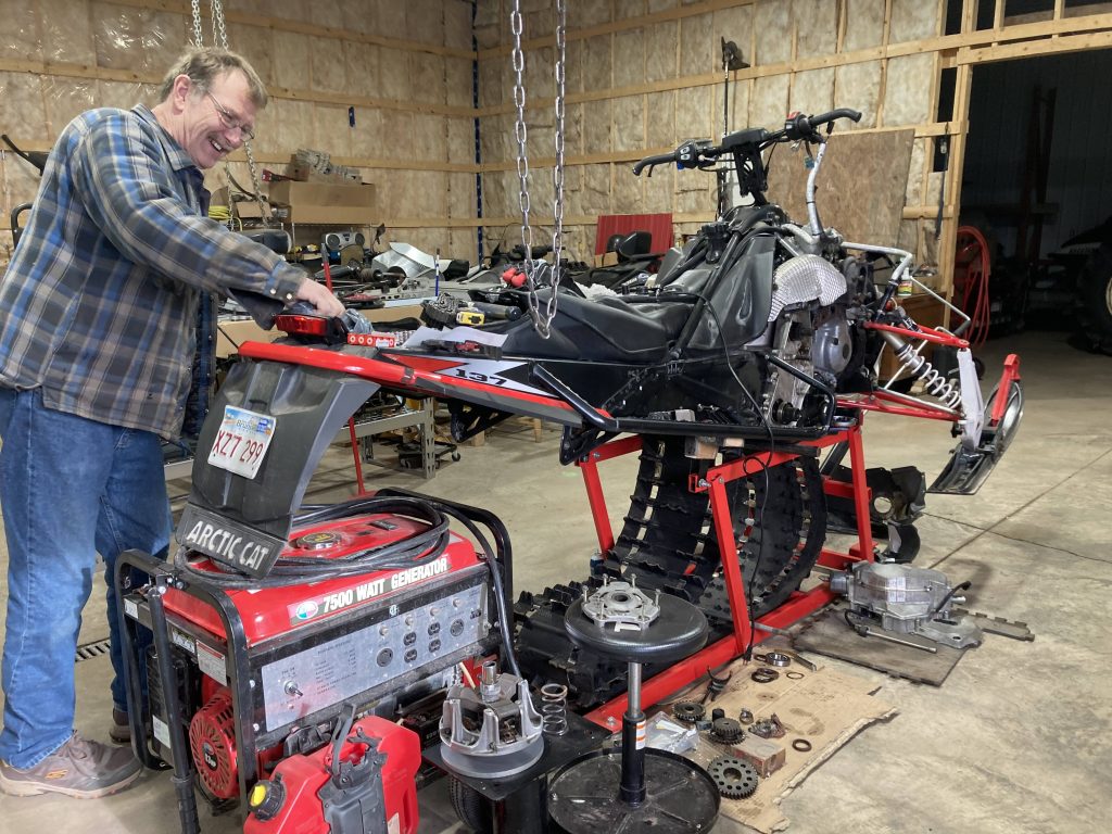 Rick Fowler working on his snowmobile in a garage