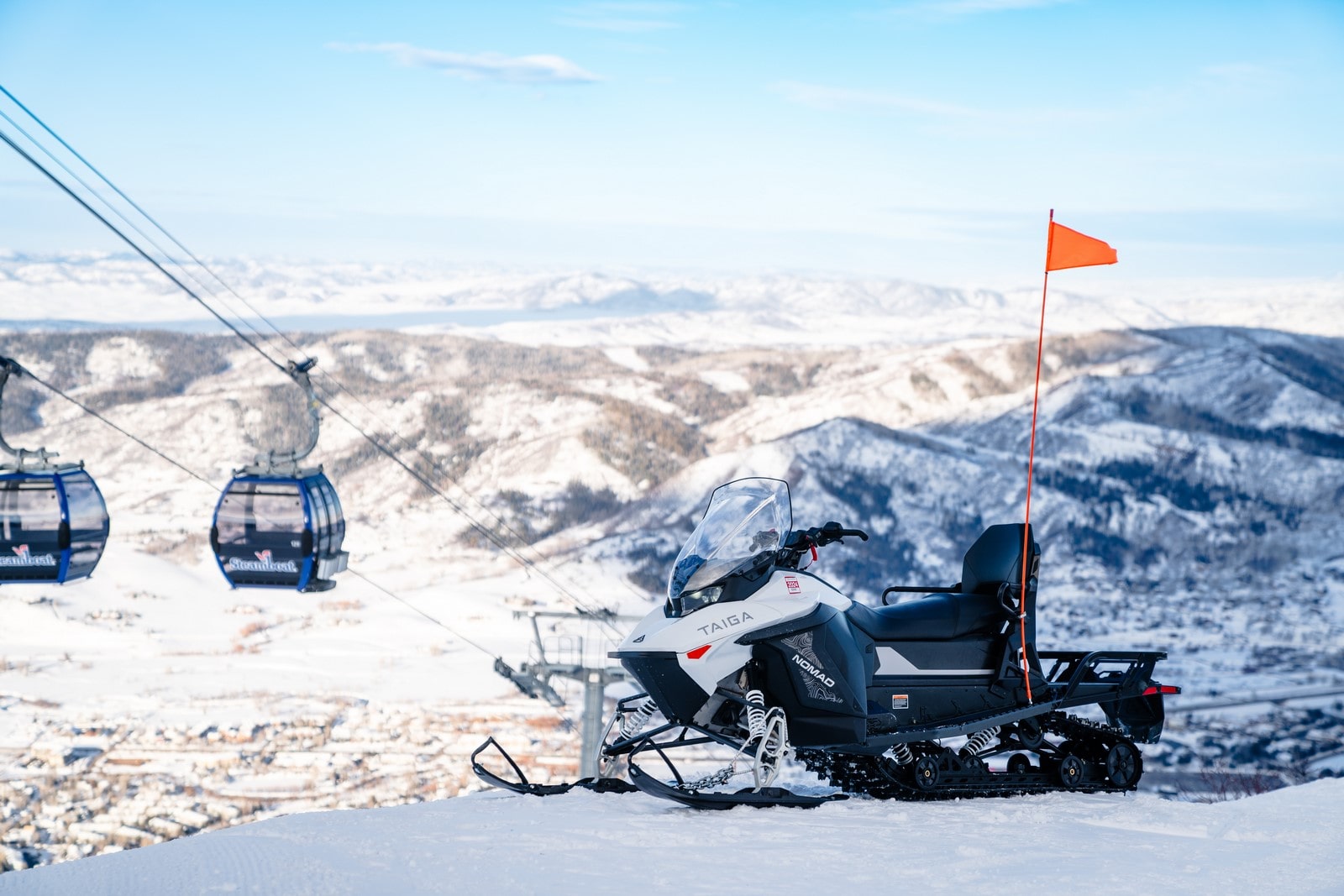 motoneiges électriques Taïga devant une montagne de ski Alterra