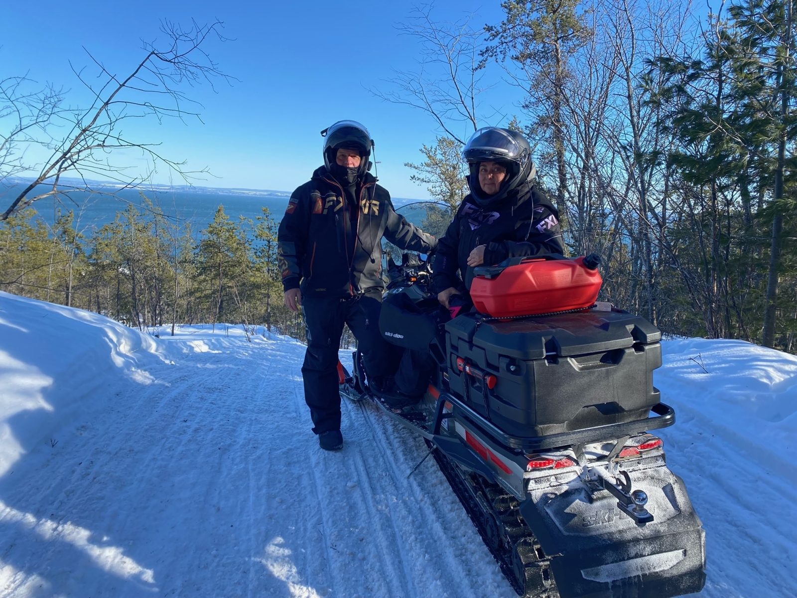 two people by their snowmobile on a trail in charlevoix