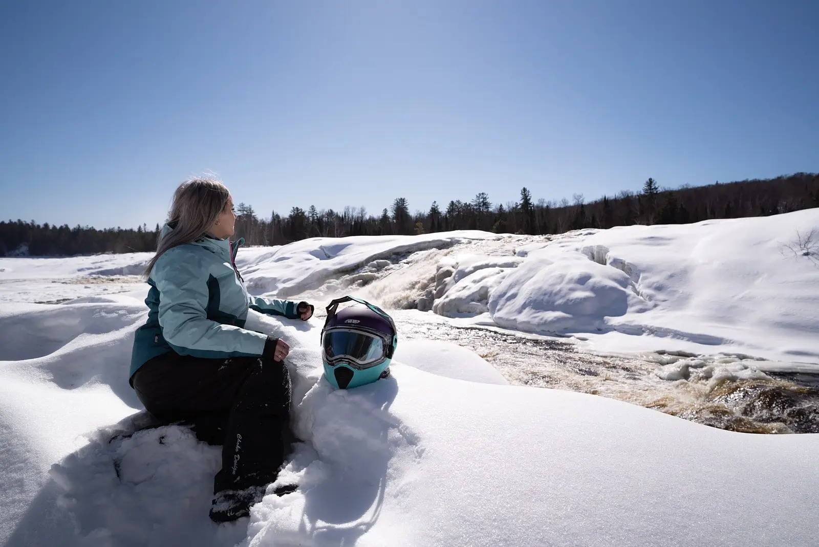 A woman sits in the snow near César Falls in the Laurentians