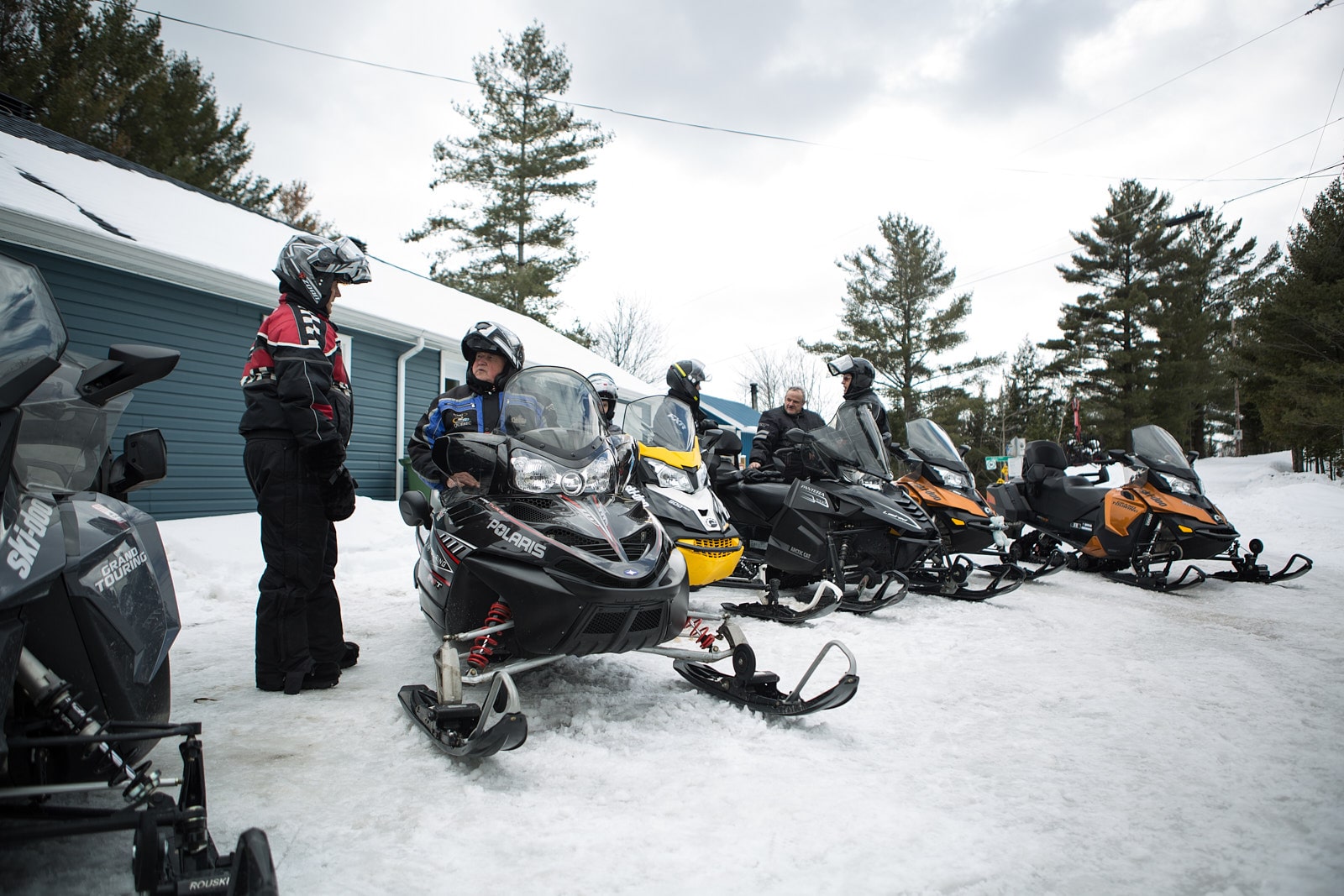 A group of snowmobilers is talking next to their parked snowmobiles, ready for an outing on the trails of Centre-du-Québec.