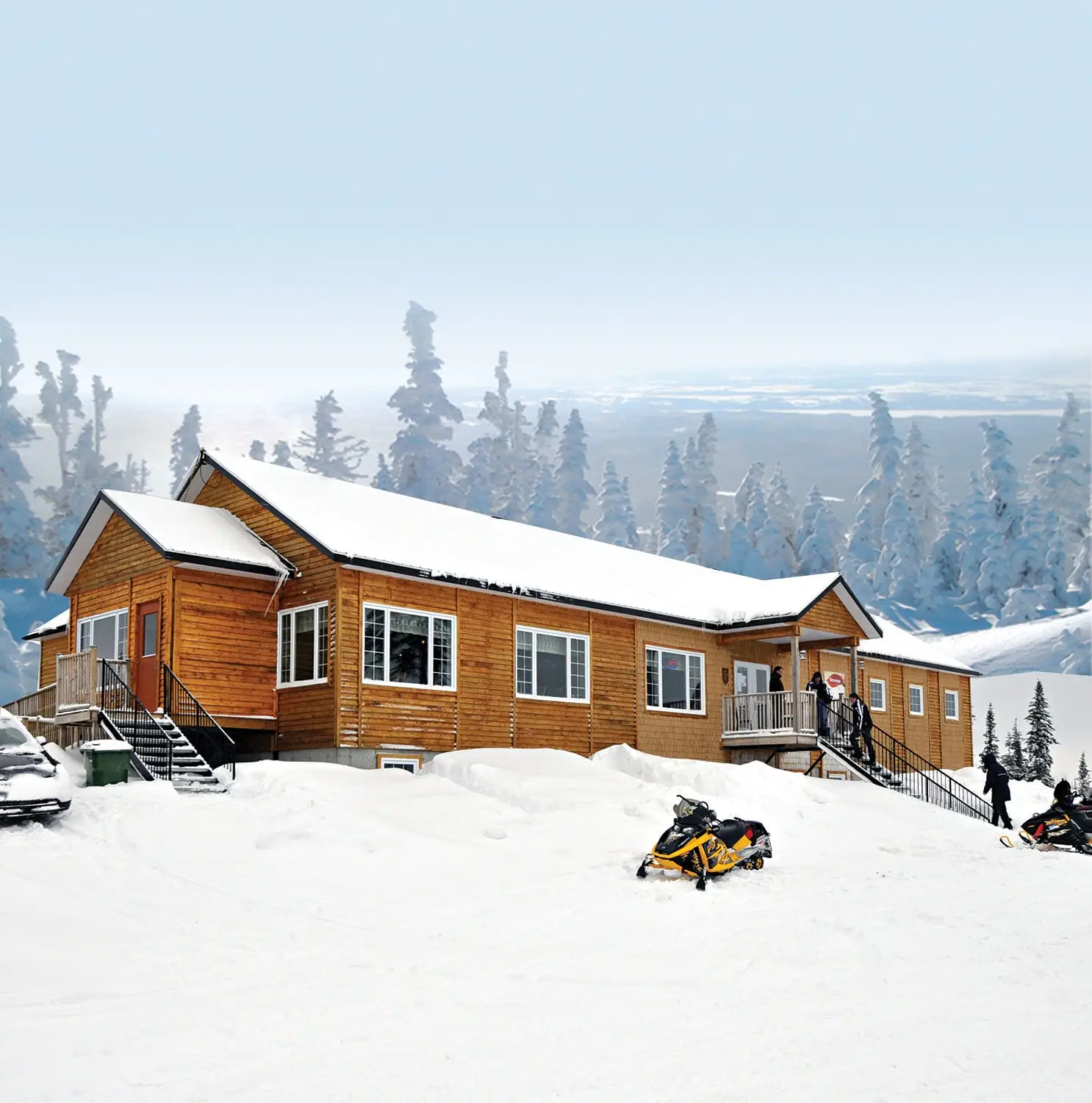 The cozy facade of Auberge du km 31, nestled amidst snowy trees.