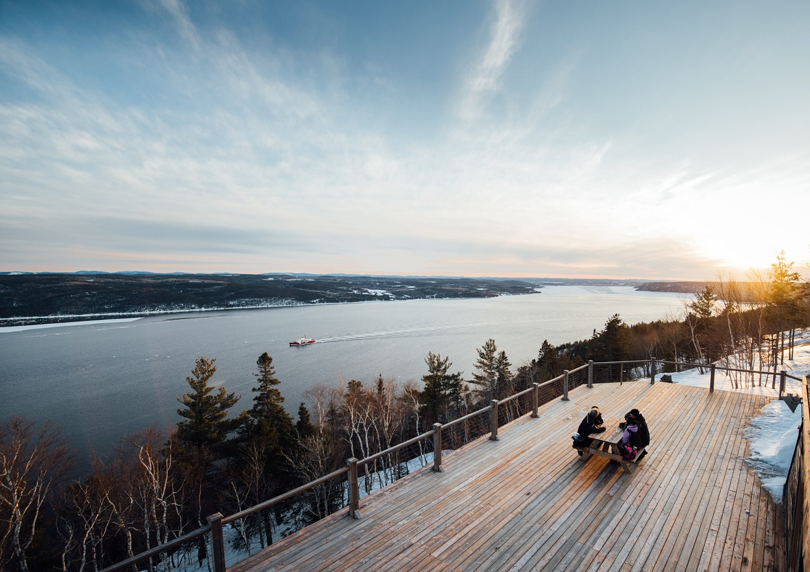 Motoneiges traversant une vallée entourée de forêts enneigées dans les sentiers de motoneige au Saguenay–Lac-Saint-Jean.