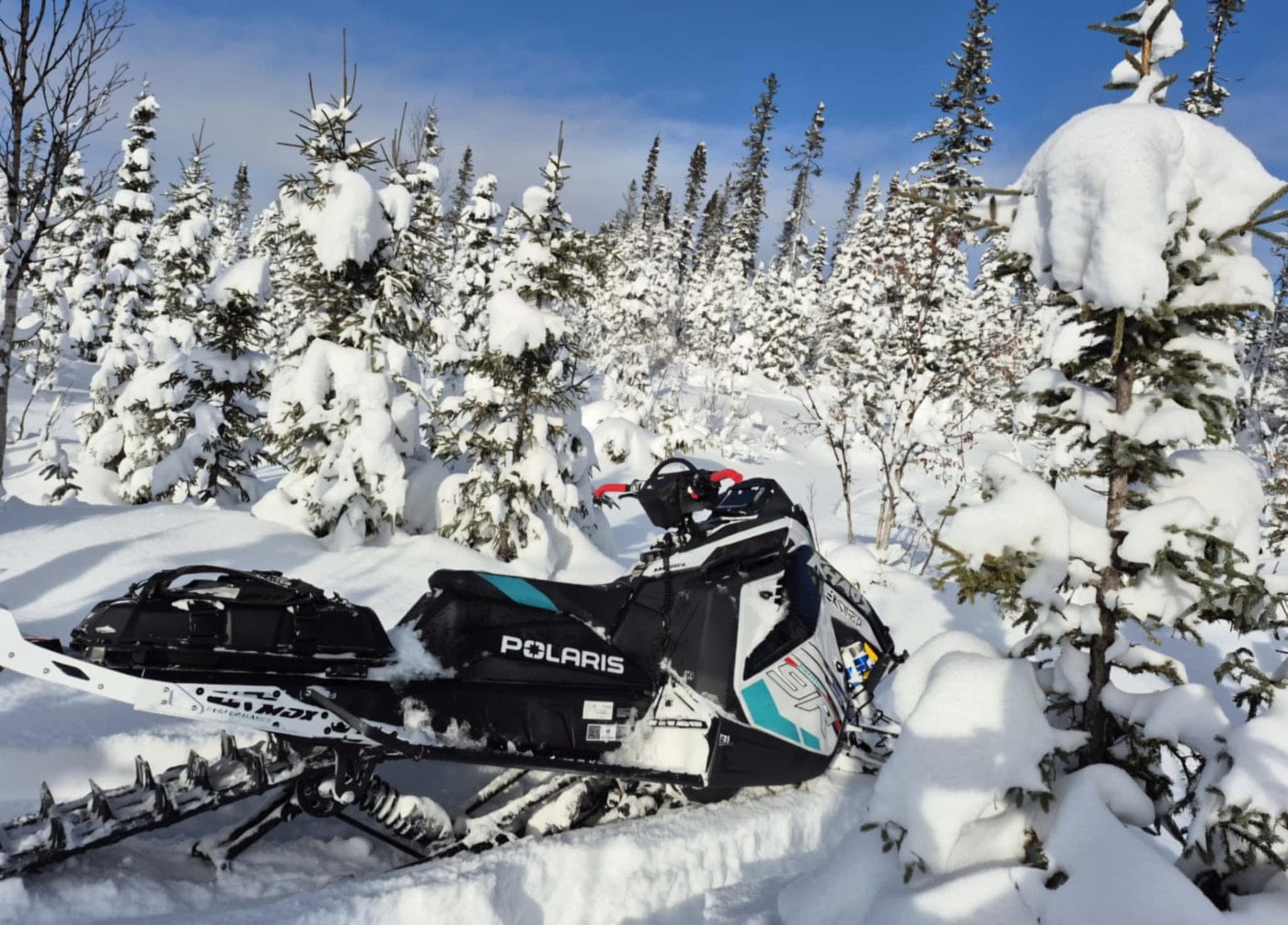 motoneige polaris Patriot 9R RMK Khaos Slash 2025 au milieu d'une forêt enneigée